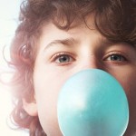 Image of young boy blowing bubble with chewing gum
